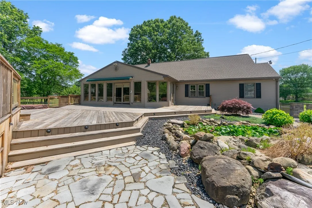 Back of property with a wooden deck and roof with shingles