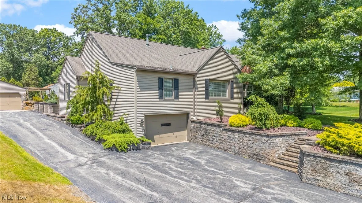 View of front of house with a shingled roof, driveway, and an attached garage