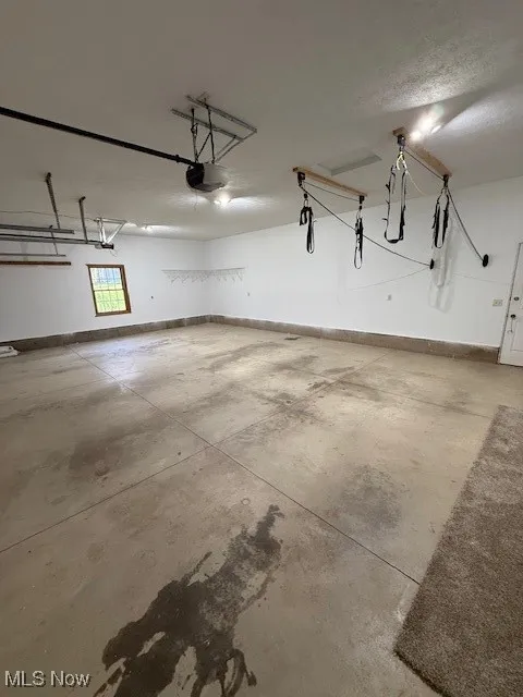 Garage featuring baseboards and a garage door opener