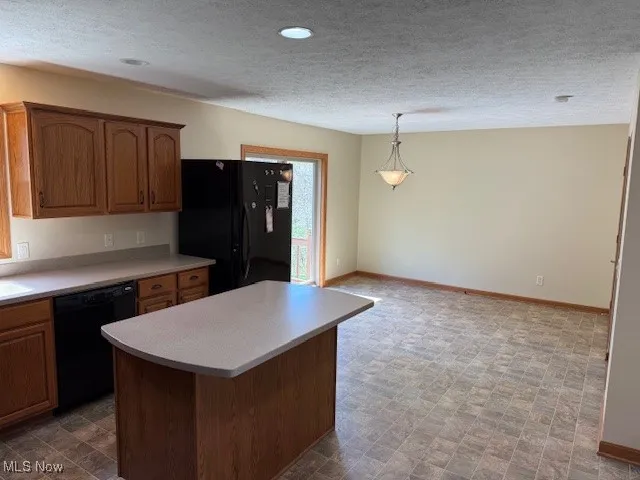 Kitchen with black appliances, baseboards, a textured ceiling, and light countertops