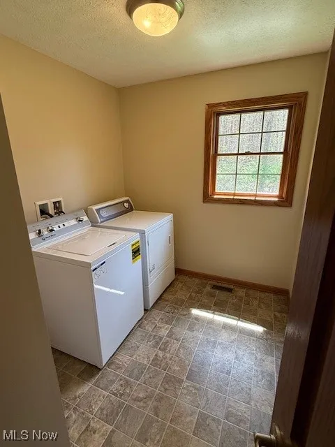 Clothes washing area featuring a textured ceiling, laundry area, baseboards, visible vents, and independent washer and dryer