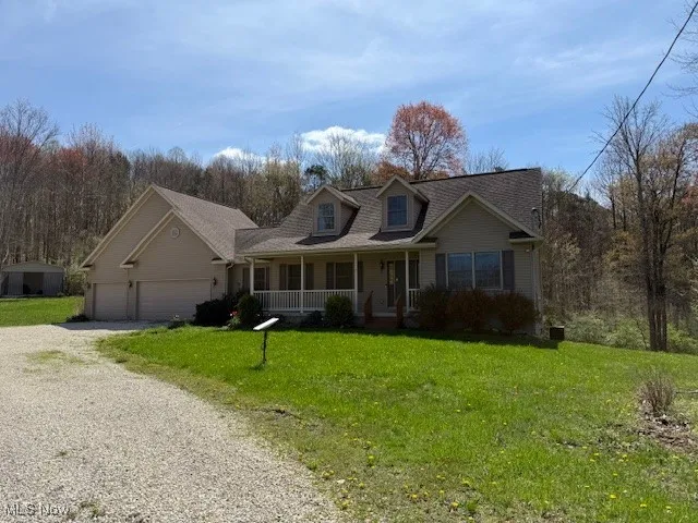 Cape cod house featuring a garage, gravel driveway, a front lawn, and covered porch