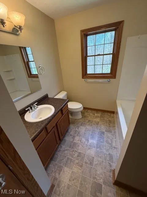 Full bath featuring toilet, a washtub, baseboards, a shower, and vanity