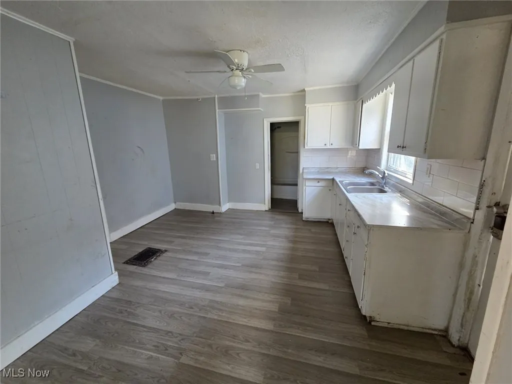 Kitchen featuring white cabinets, a sink, tasteful backsplash, visible vents, and ornamental molding