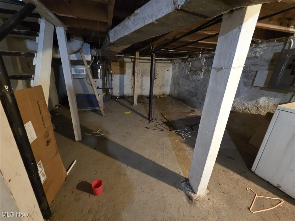 Unfinished basement featuring electric panel, gas water heater, and washer / clothes dryer