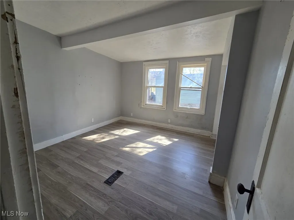 Spare room with baseboards, beam ceiling, and dark wood finished floors