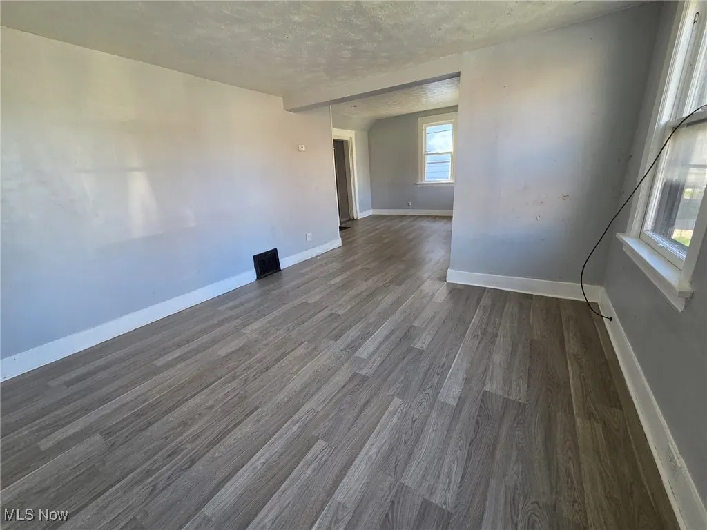 Spare room featuring baseboards, a textured ceiling, and dark wood-style floors