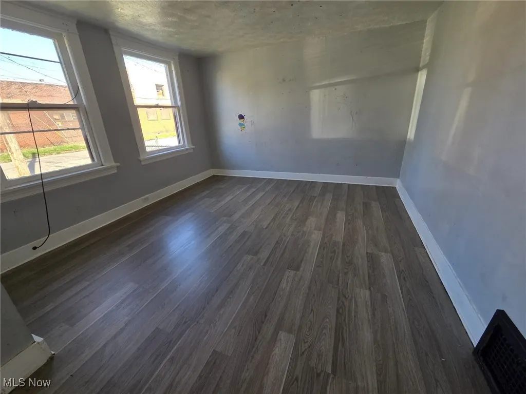 Spare room featuring baseboards, a textured ceiling, dark wood-style floors, and visible vents