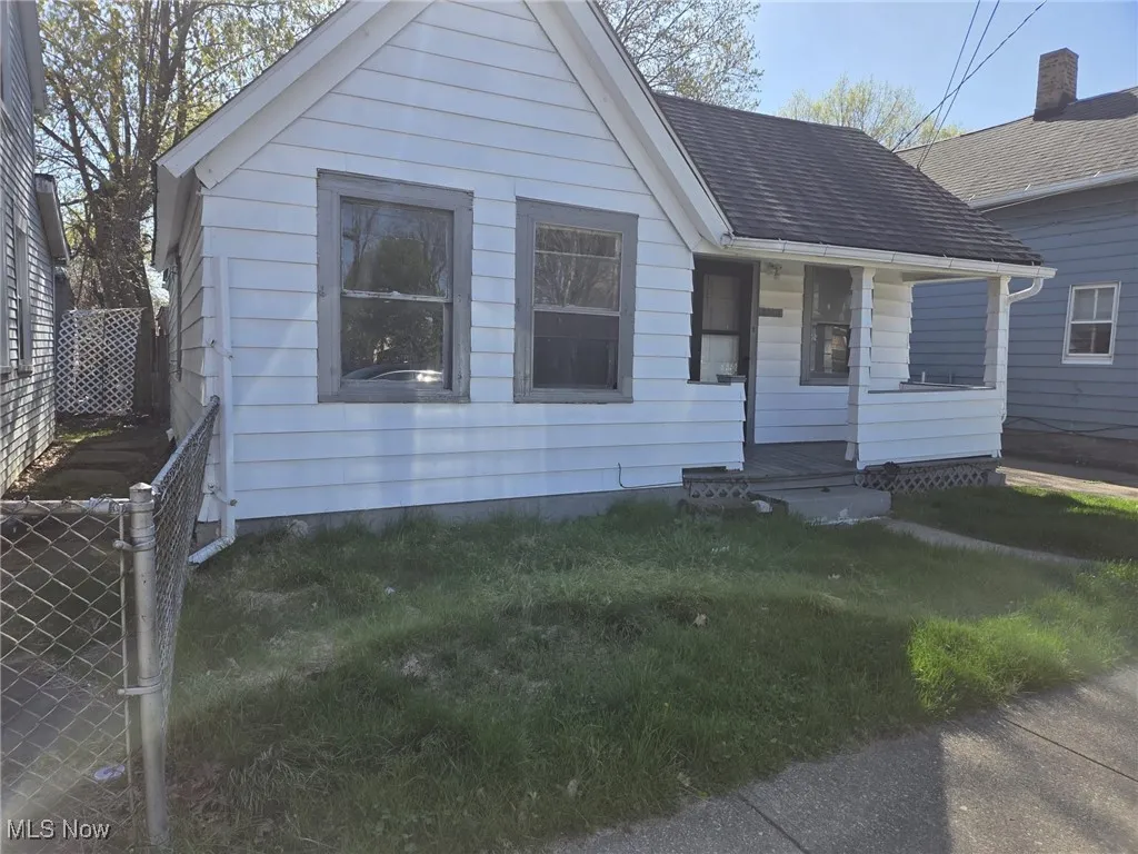 Bungalow-style house featuring fence, a front lawn, and roof with shingles