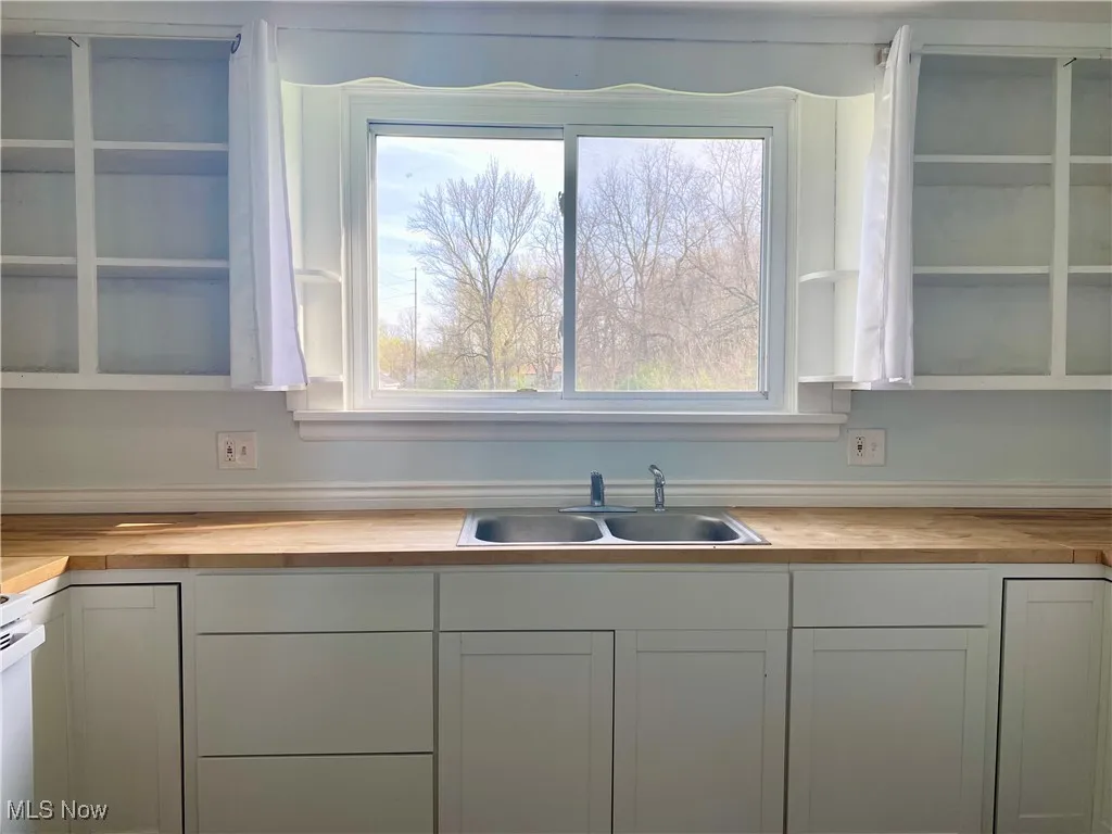 Kitchen with white cabinets, a sink, and wooden counters