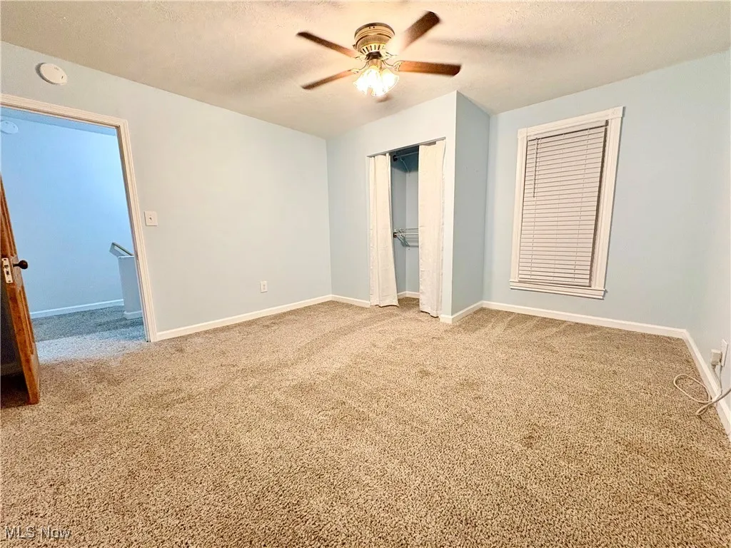 Unfurnished bedroom with carpet floors, a closet, a textured ceiling, and baseboards