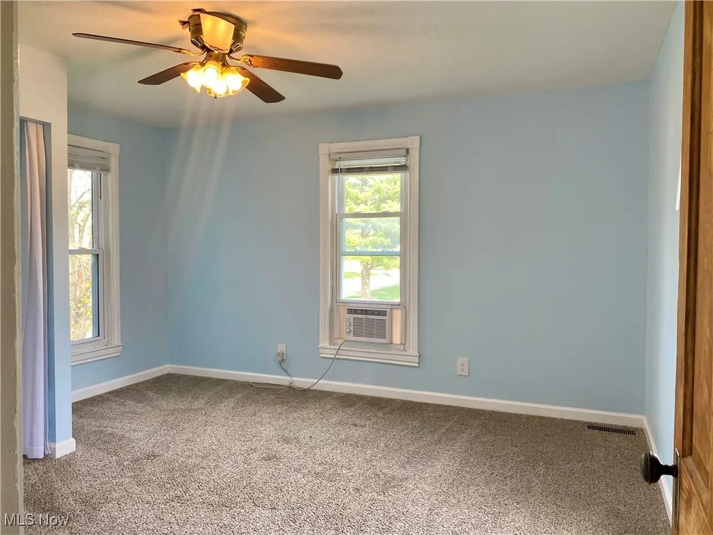 Spare room with baseboards, carpet, visible vents, and cooling unit