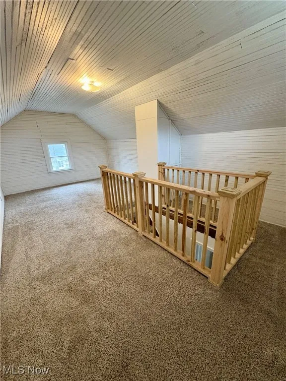 Additional living space with lofted ceiling, wood walls, carpet floors, and wood ceiling