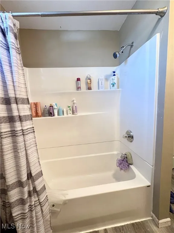 Full bathroom with shower / bath combo and wood finished floors