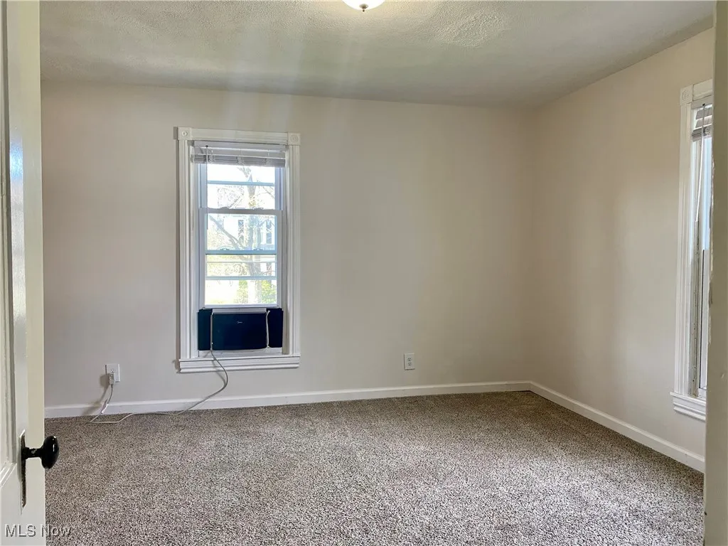 Unfurnished room with cooling unit, carpet flooring, and baseboards