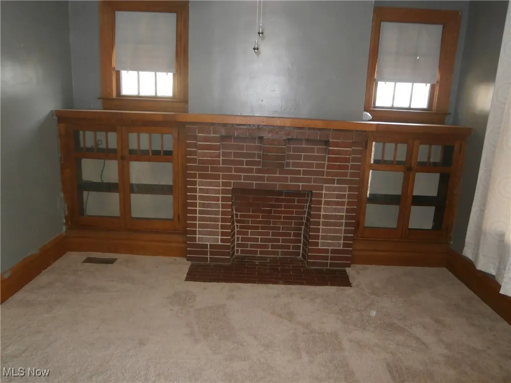 Unfurnished living room featuring a tile fireplace, visible vents, carpet flooring, and a healthy amount of sunlight