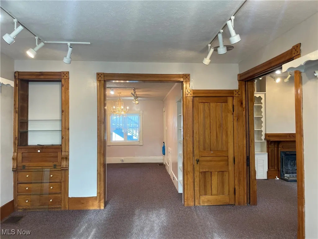 Hall featuring baseboards, visible vents, carpet, an inviting chandelier, and track lighting