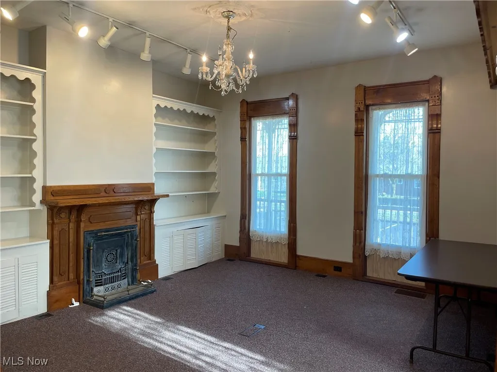 Unfurnished living room featuring a fireplace, track lighting, and plenty of natural light