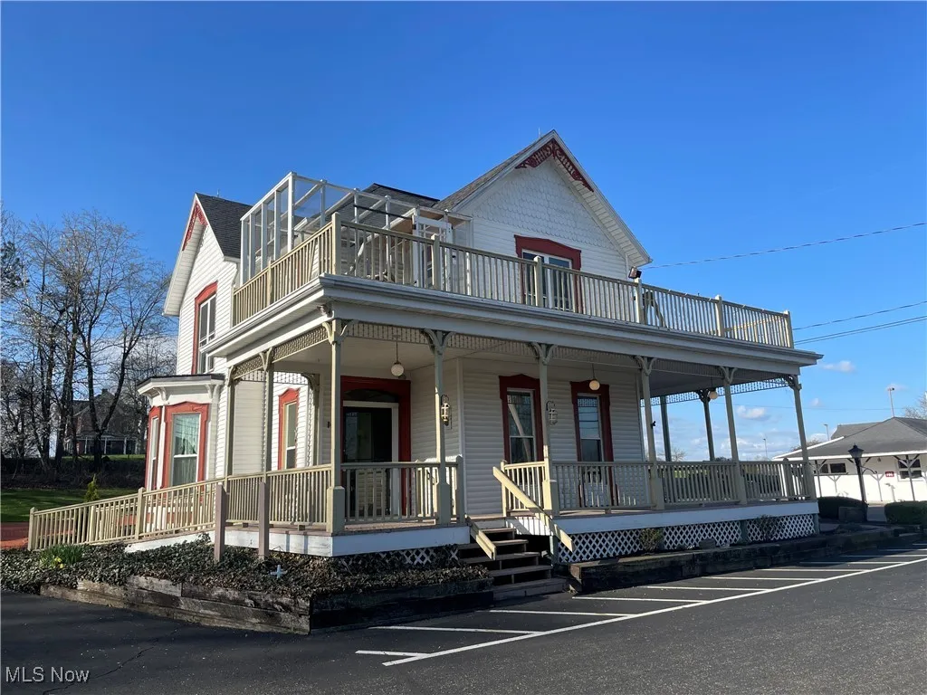 View of front of property featuring a porch and a balcony