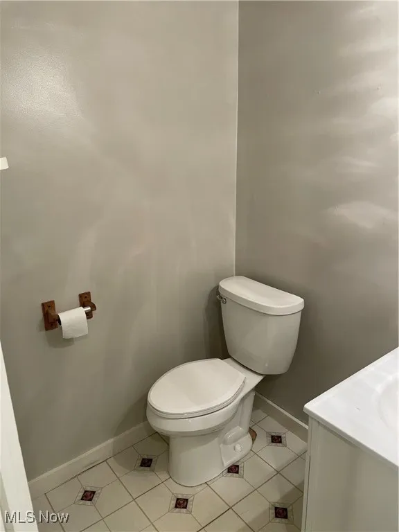 Half bath with tile patterned floors, baseboards, and toilet