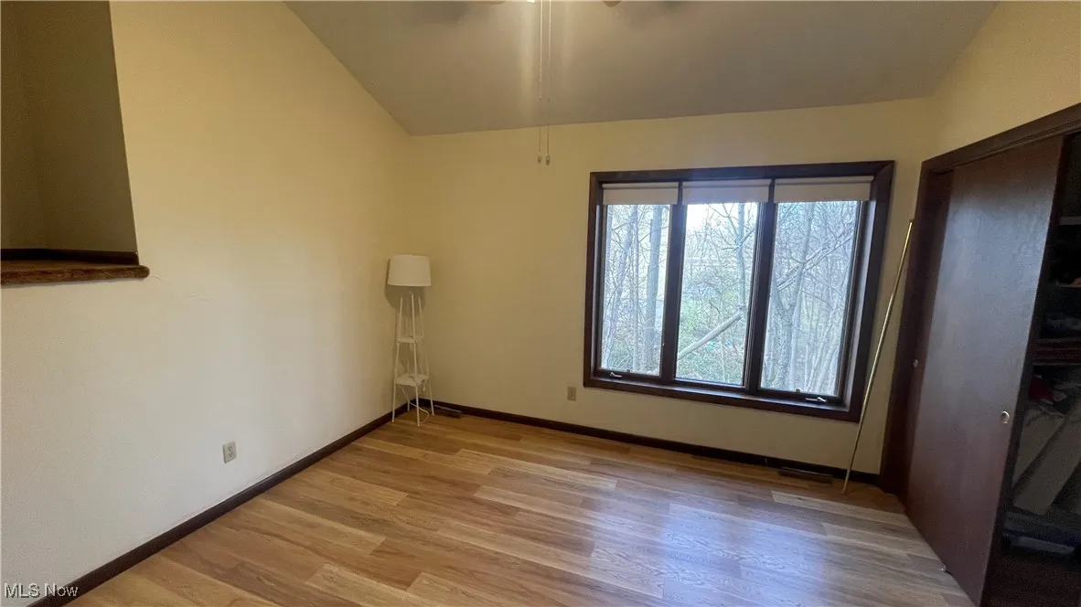 Unfurnished room featuring light wood-style flooring, lofted ceiling, and baseboards
