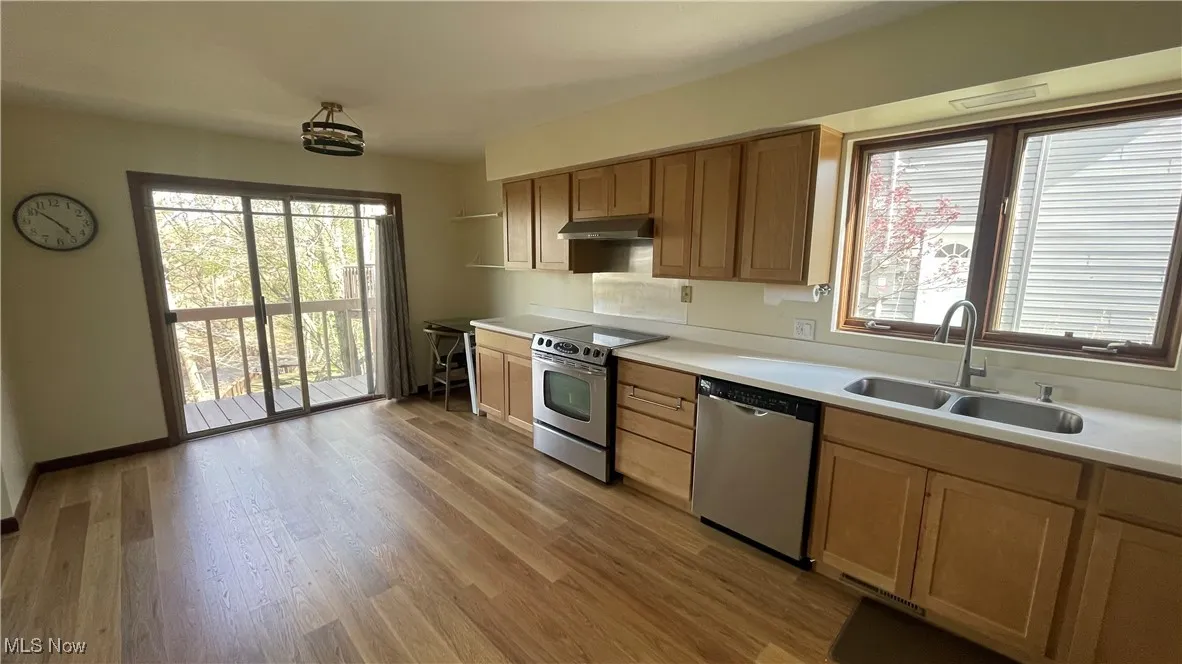Kitchen with light countertops, light wood-type flooring, stainless steel appliances, and a sink