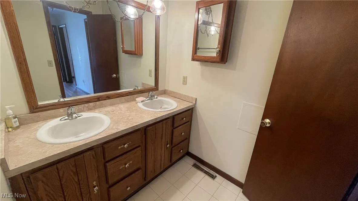 Full bathroom featuring double vanity, visible vents, baseboards, and a sink