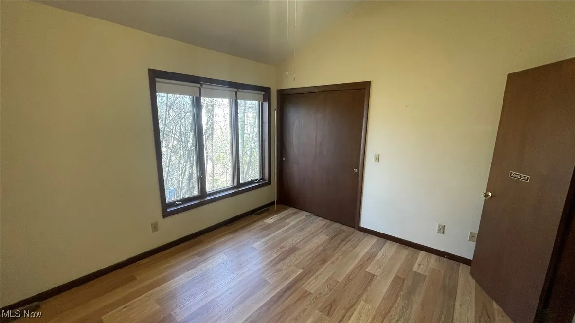 Unfurnished bedroom featuring light wood-type flooring, vaulted ceiling, baseboards, and a closet