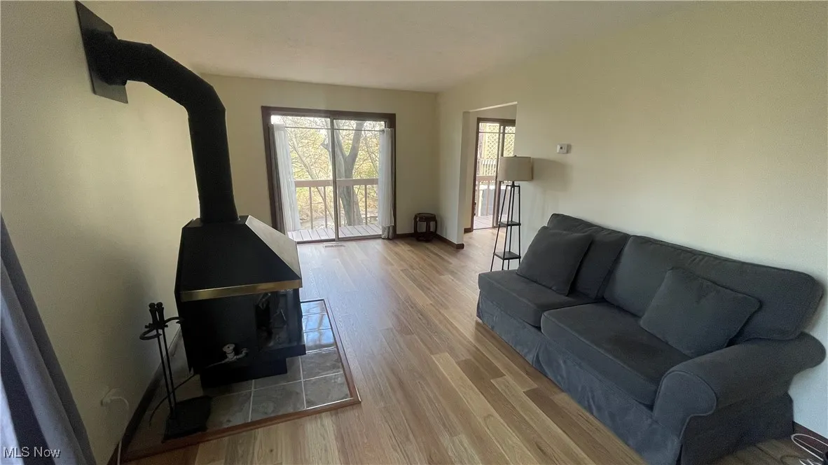 Living area with baseboards, a wood stove, and wood finished​​‌​​​​‌​​‌‌​‌‌​​​‌‌​‌​‌​‌​​​‌​​ floors