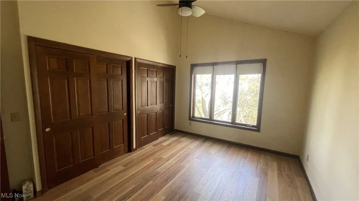 Unfurnished bedroom with baseboards, high vaulted ceiling, light wood-style floors, and ceiling fan