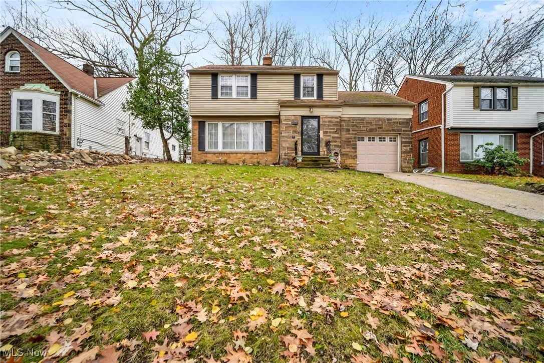 View of front of home with a chimney, an attached garage, driveway, and a front lawn