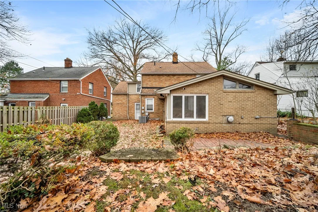 Rear view of house with fence, brick siding, and central AC