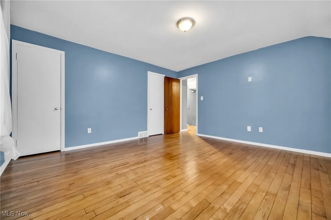 Unfurnished bedroom with wood-type flooring, baseboards, and visible vents