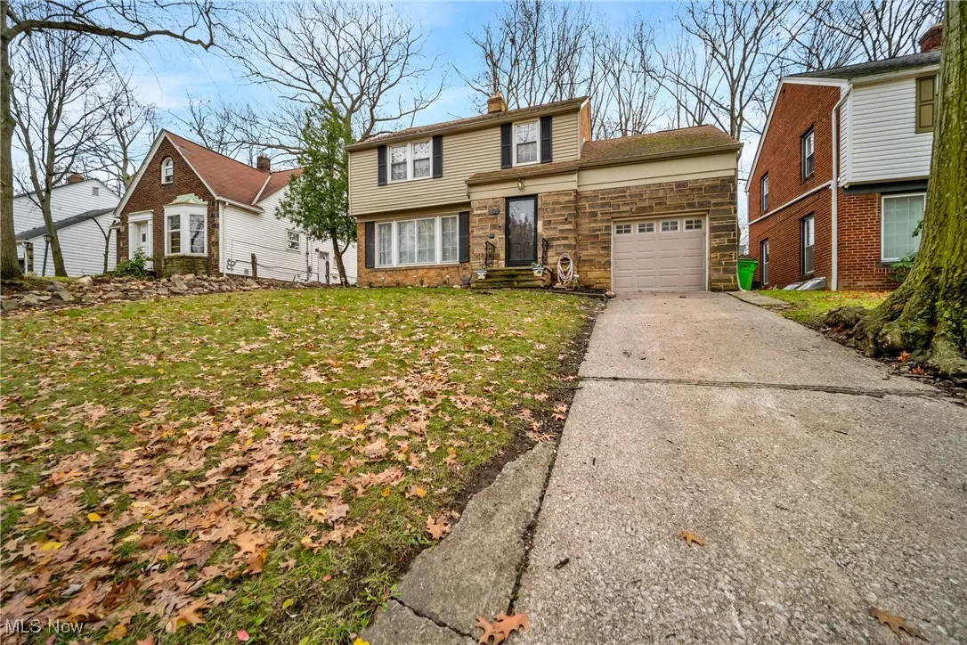 View of front of property featuring a garage, stone siding, a chimney, and concrete driveway
