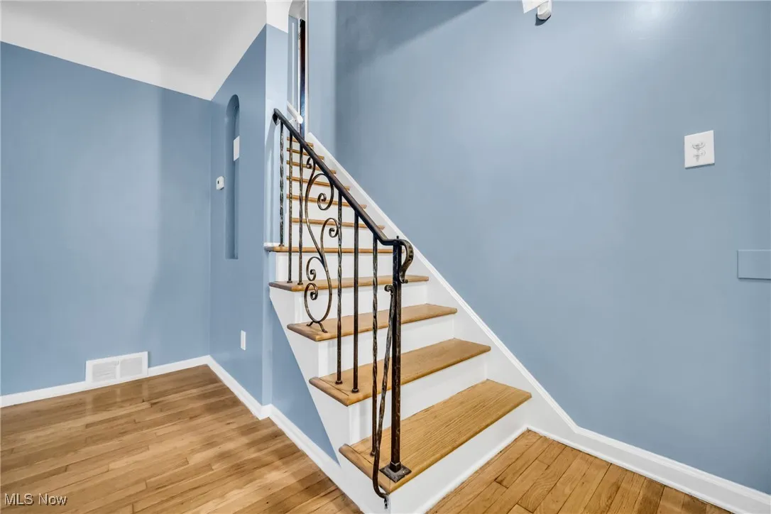 Staircase with wood finished floors, visible vents, and baseboards
