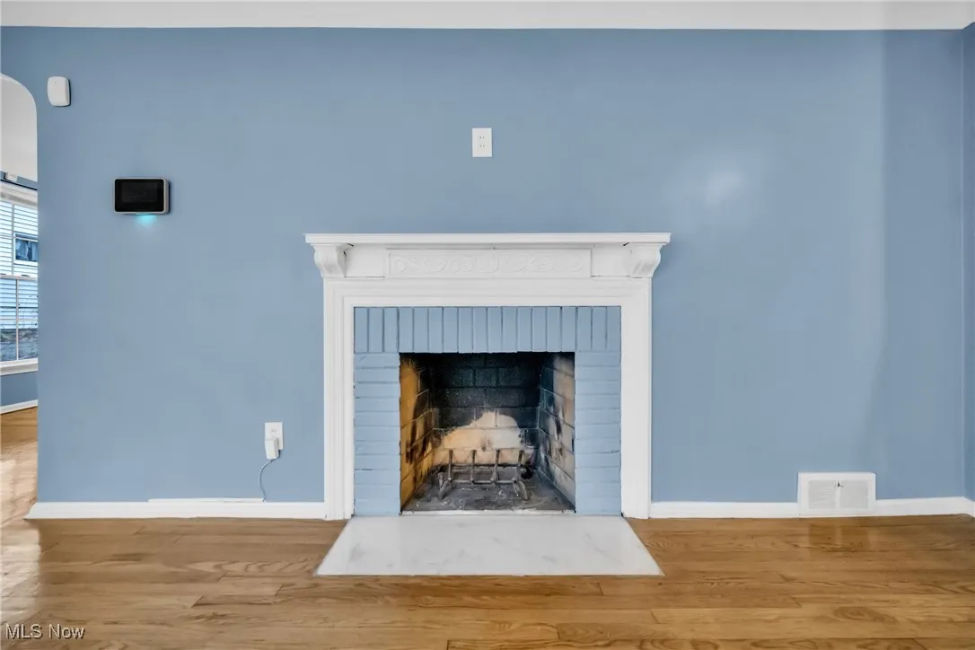 Interior details with wood finished floors, baseboards, a brick fireplace, and visible vents