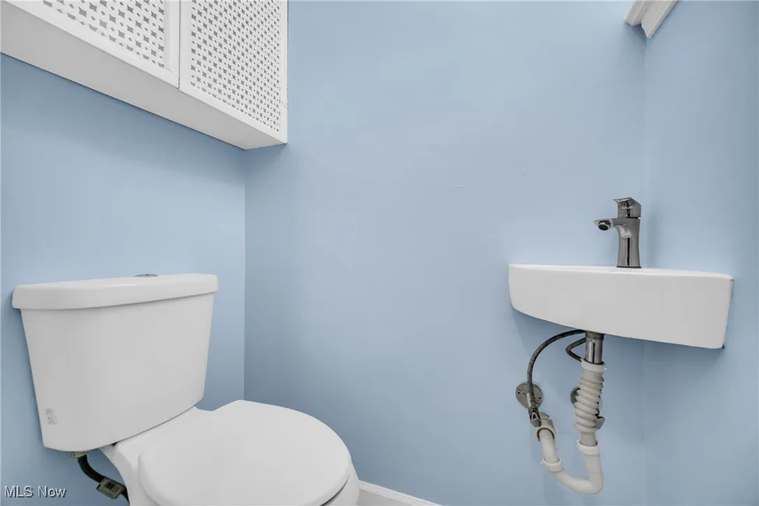 Half bath with toilet, a sink, and baseboards