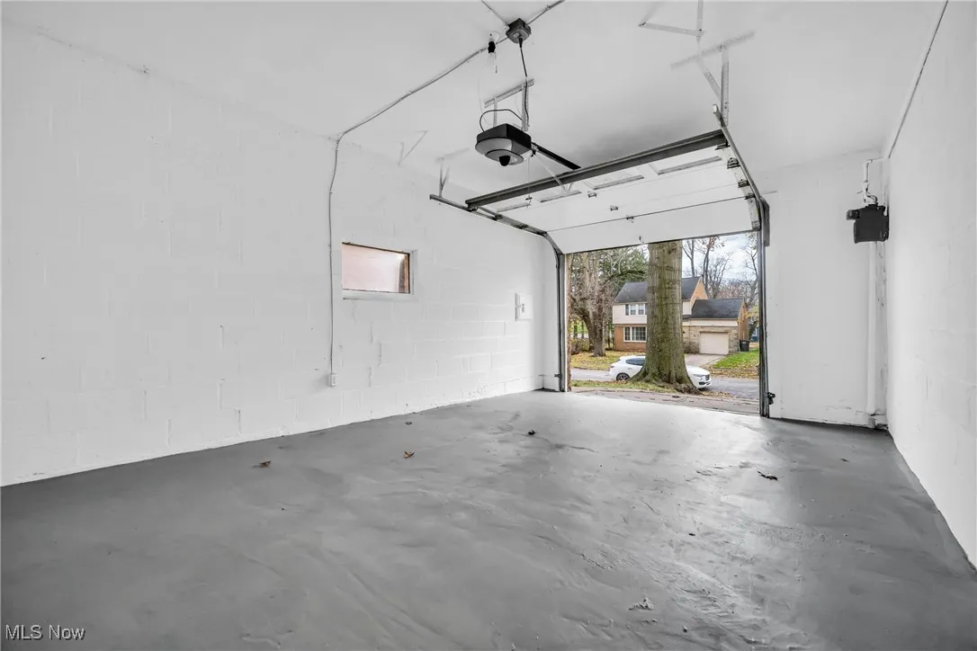 Garage featuring concrete block wall and a garage door opener