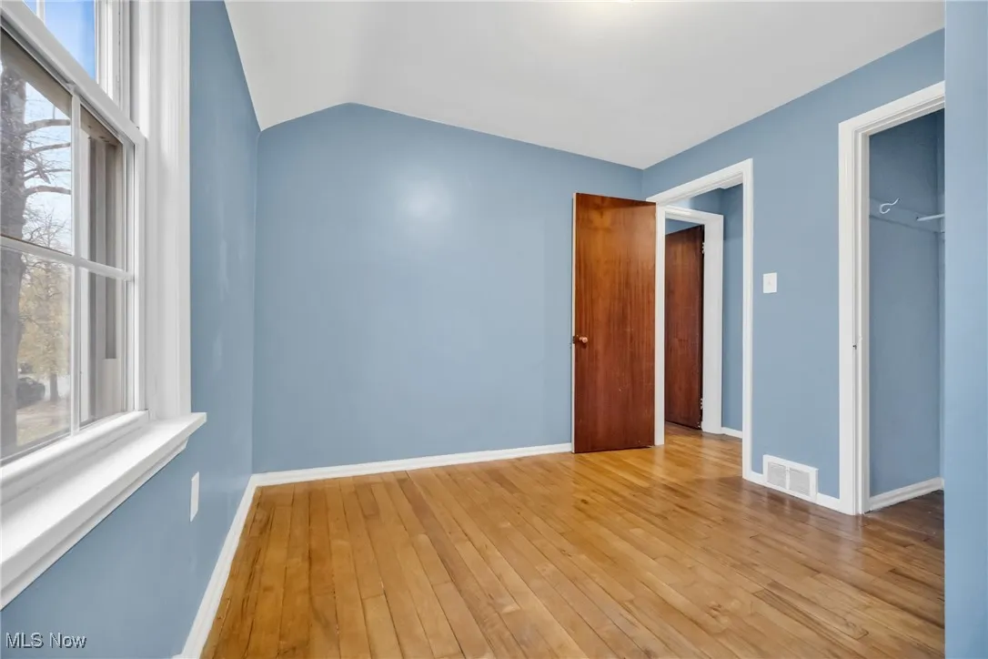 Unfurnished room featuring vaulted ceiling, baseboards, light wood-style floors, and visible vents