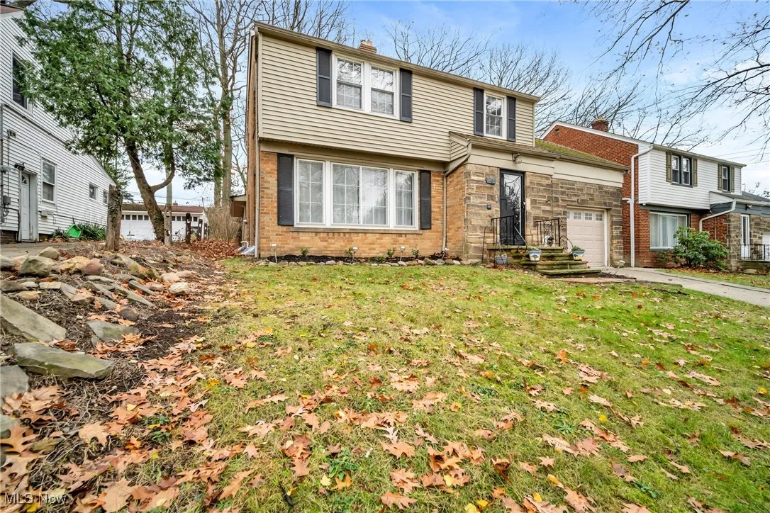 View of front of property featuring a garage, a chimney, driveway, a front yard, and brick siding