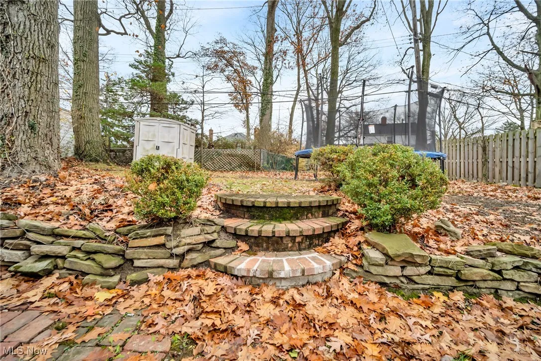 View of yard featuring an outdoor structure, a storage unit, a trampoline, and a fenced backyard