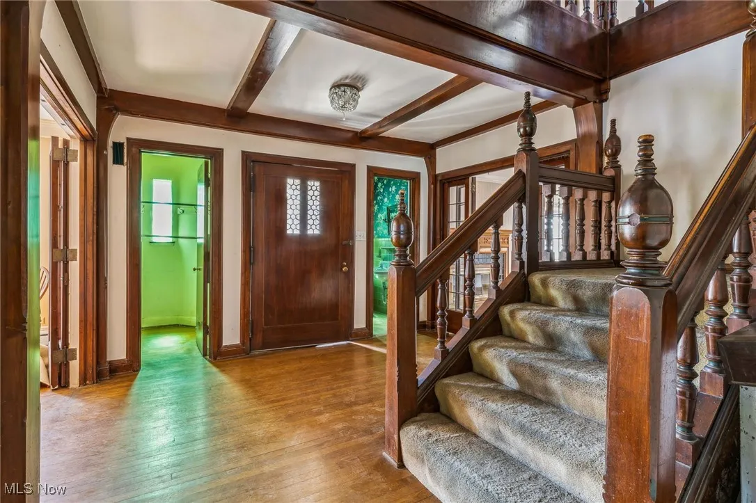 Foyer entrance featuring hardwood / wood-style flooring, baseboards, beam ceiling, and stairs