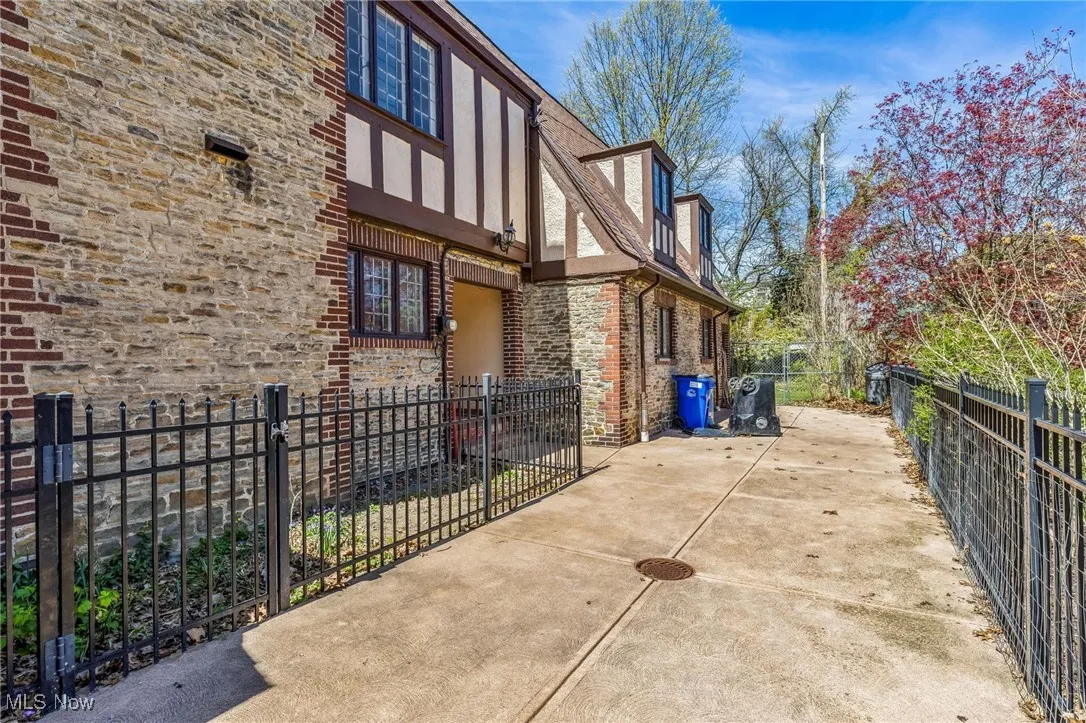 View of property exterior featuring fence private yard, a patio area, and stone siding