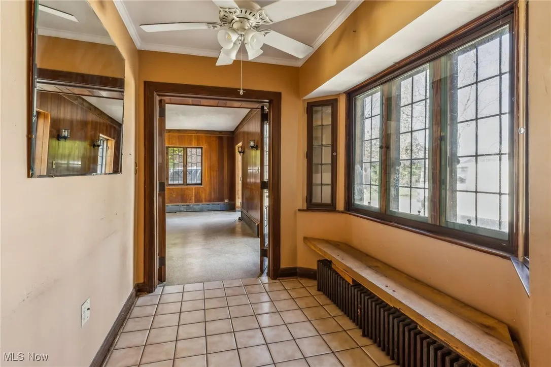 Corridor featuring wooden walls, baseboards, ornamental molding, and radiator
