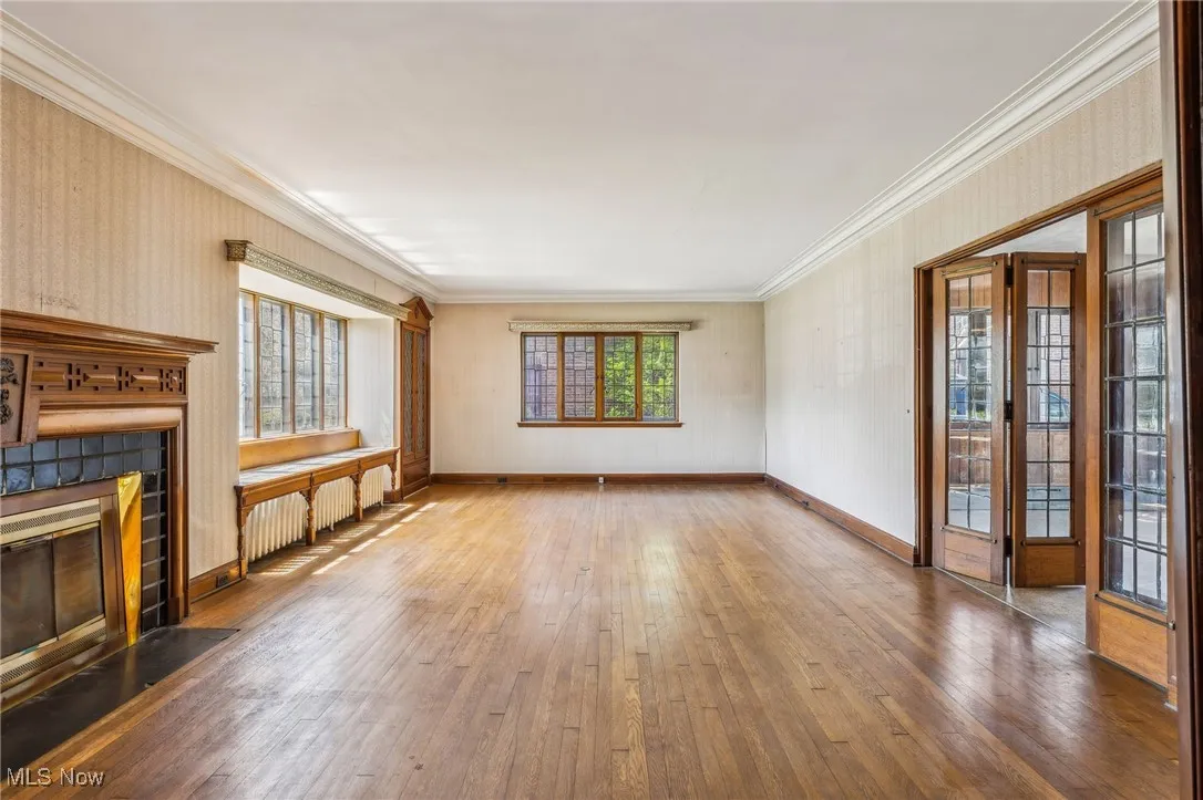 Unfurnished living room with a fireplace with flush hearth, hardwood / wood-style floors, and crown molding
