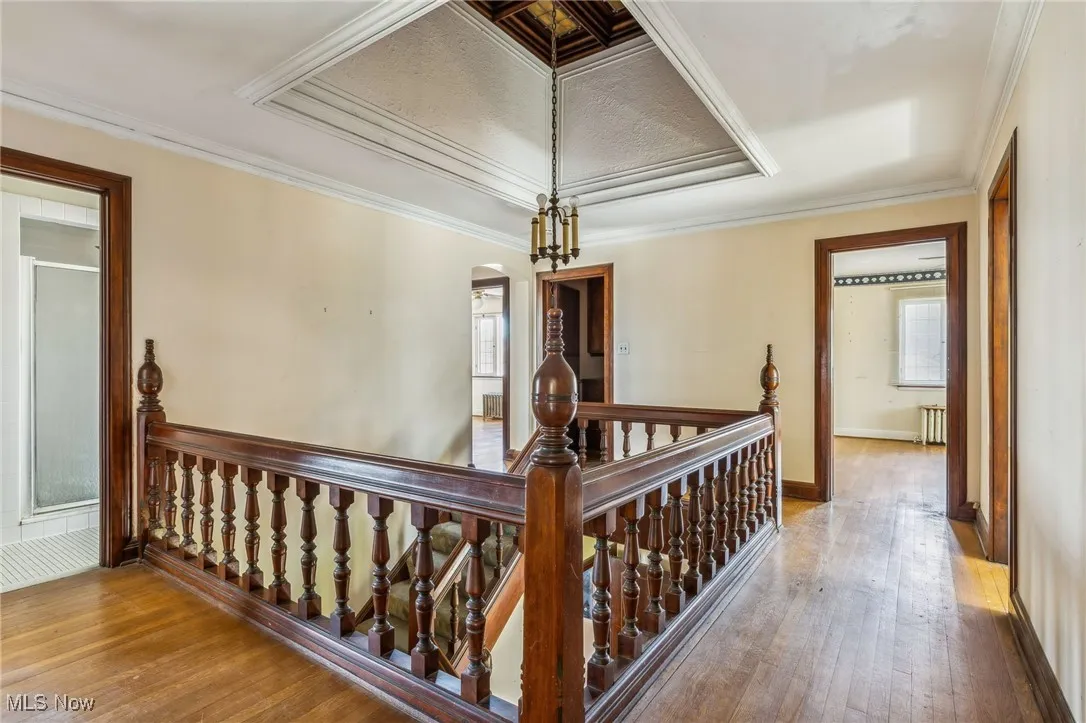 Corridor with radiator, arched walkways, an upstairs landing, and wood-type flooring