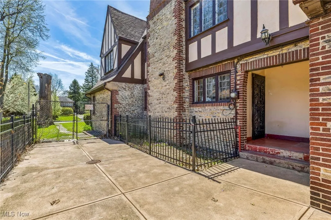 View of property exterior with a gate, brick siding, stucco siding, and fence