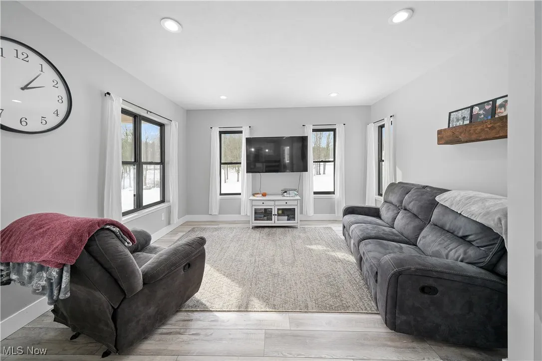 Living area with baseboards, recessed lighting, wood finished floors, and plenty of natural light