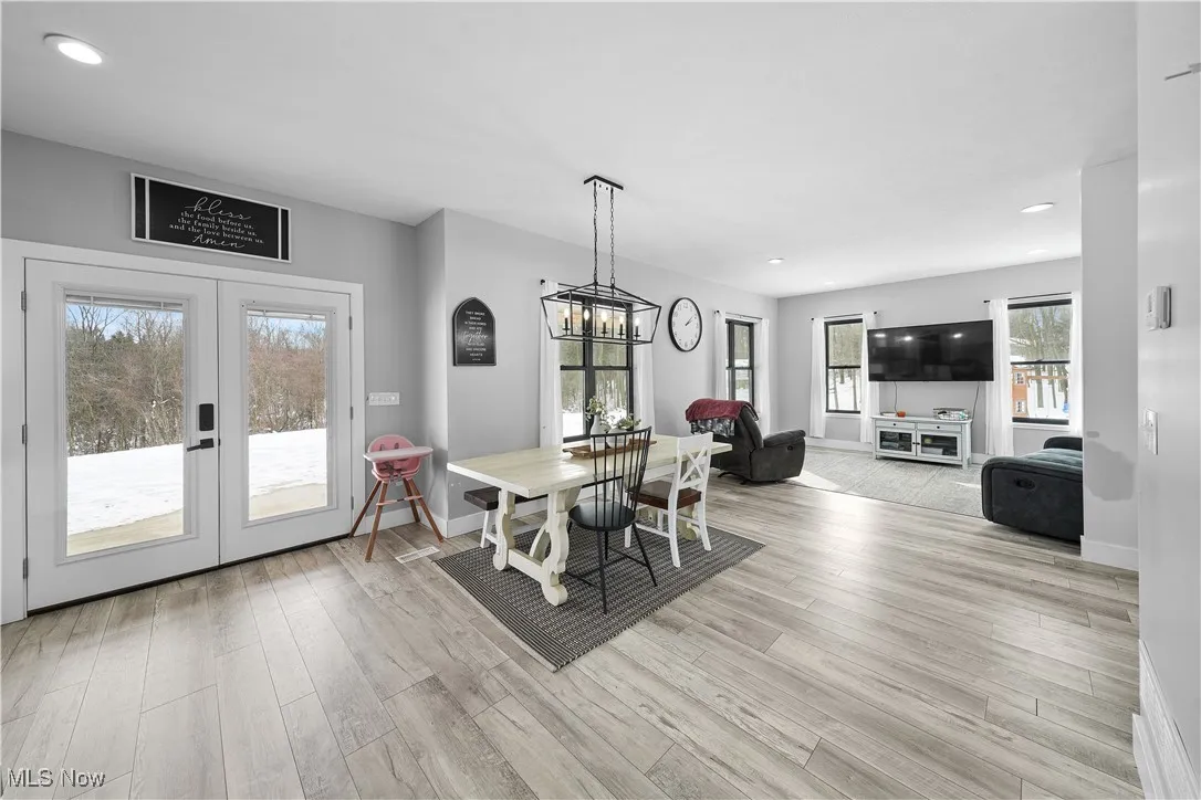 Dining room featuring french doors, light wood-style flooring, baseboards, recessed lighting, and a notable chandelier