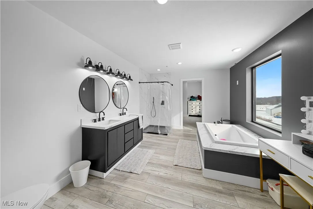 Bathroom featuring curtained shower, recessed lighting, wood finished floors, visible vents, and vanity
